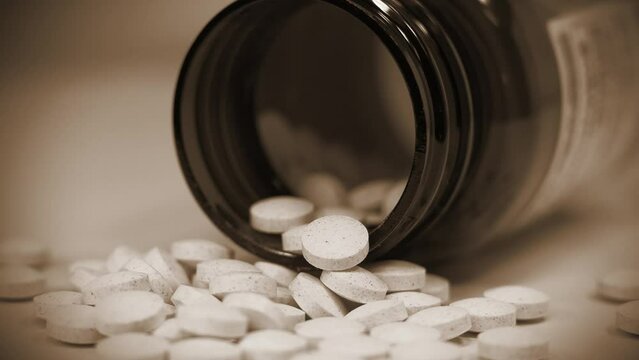 Tablets and jar lies on the table. Theme of poisoning or overdose, high doses and side effects. Pharmaceutical and food additive industry. Biochemistry, drug therapy. 4K video with cinema effects