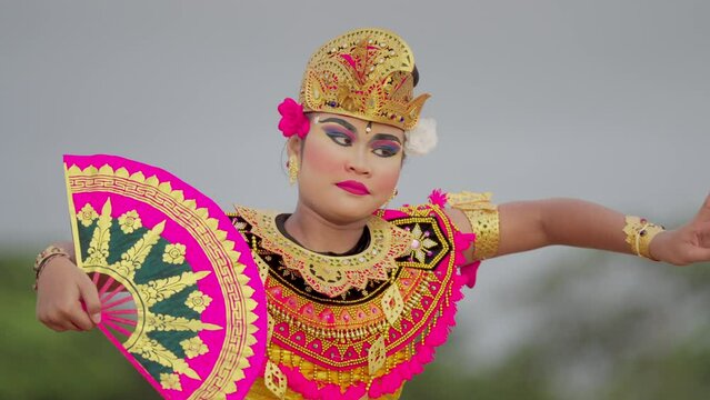 slow motion shot of authentic balinese dancer with fan and traditional costume