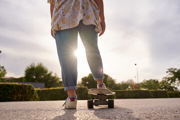 close-up detail of a woman's legs with a skateboard and the sun shining in the background