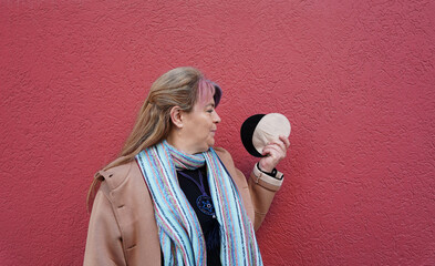 Mature woman holding ostomy bags on red background. World Cancer Day