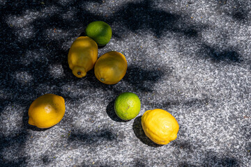 Close-up of lemons on a stone background with the shade of a tree in a garden