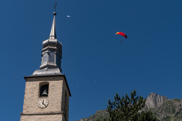 Paragliders flying over the bell tower of the church of Saint Michel with Le Brevent peak in the...