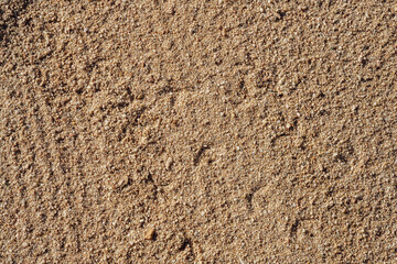 Brown sandy road with small pebbles and dirt. Detail of surface texture with small pebble rock on dirty ground.