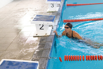 Caucasian female athlete swimmer finishes a swim in a pool lane