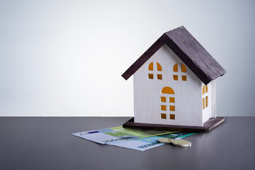 Fototapeta na wymiar Model house and money euro banknotes on grey background with copy space. Home loan, tax of house, buy of home, mortgage concept.