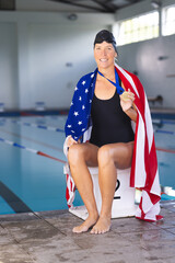 Caucasian woman draped in an American flag at a poolside, with medal, with copy space