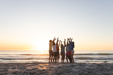 Naklejka premium Diverse group celebrates on the beach at sunset