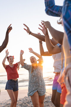 Diverse young friends enjoy a beach party at sunset, with copy space