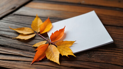 Obraz premium A white sheet of paper on a wooden surface surrounded by autumn leaves. Layout for a postcard. Concept 