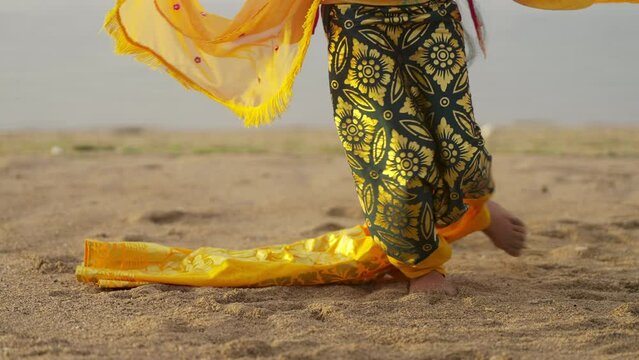 Slow motion close-up of young balinese dancer dancing on beach barefoot, bali