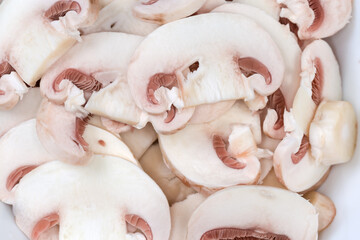 Background of raw sliced button mushrooms, top view close-up