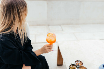 woman drinking and holding a cocktail Aperol Spritz 