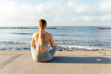 Fototapeta na wymiar A young girl sitting on the beach with yoga poses meditation 