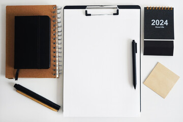 Clip folder with paper next to notepads, calendar, stickers and pens on white background