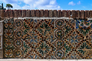Terrace brick wall covered with colorful tiles against blue sky