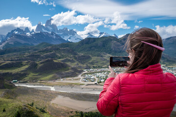Mujer tomando fotografía de El Chalten con su celular, desde el mirador nido del águila. Patagonia Argentina - obrazy, fototapety, plakaty