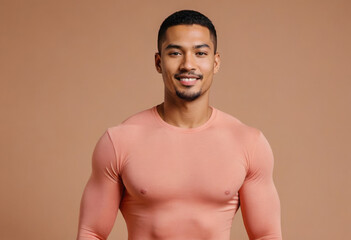 Fototapeta premium A fit man in a form-fitting peach shirt, his poise and smile suggesting confidence and a friendly demeanor.