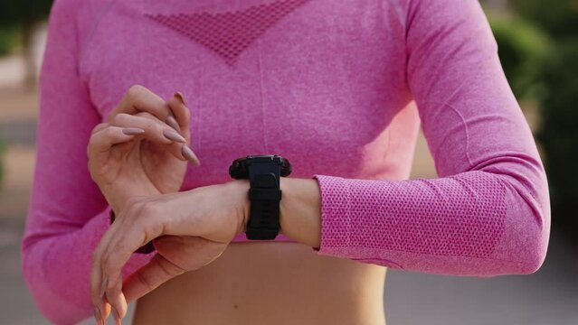 The hands of girl touch the dial of the fitness watch. A young sportswoman checks time, pulse rate and blood pressure. Close up. The shooting mode no face.