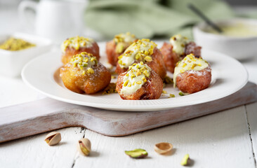 Golden Fritelle with Pistachio Cream on a Ceramic Plate, pistachio cream, napkin and milk saucer behind