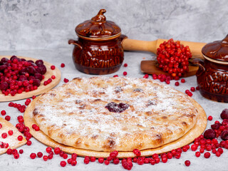 sweet Caucasian pie on a gray background surrounded by fruits and dishes