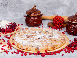 sweet Caucasian pie on a gray background surrounded by fruits and dishes
