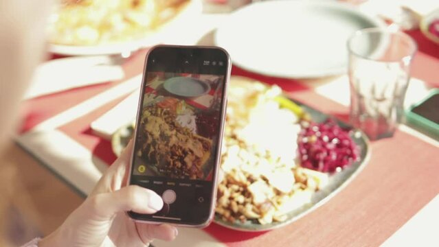 Close up top view of woman taking photo of food with digital camera of cellphone to place pictures at social media resources. Woman shooting french fried potato, green salad and chicken grilled meat.