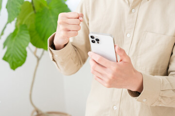 スマホを持ってガッツポーズする男性