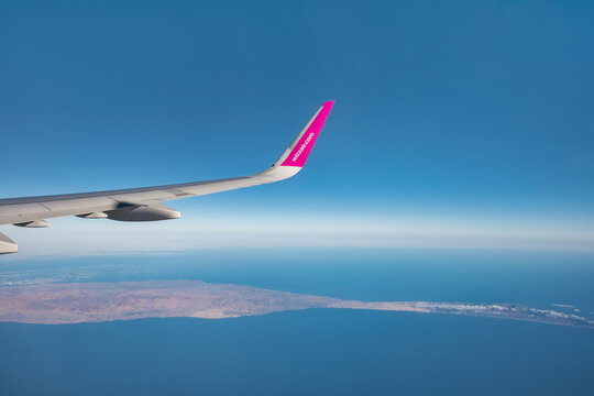 Wizz Air, Fuerteventura, Canary Islands, Spain - September 3, 2021: views from a window towards the wing with logo of the popular low-cost commercial airline, flying above one of the Canarian islands