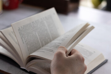 Fototapeta premium Men's hands flipping through the pages of the book. Close up view.