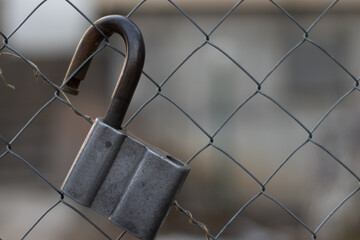 Close up view of the old open metal lock hanging on the fence. Blurred background with natural...