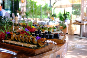 Various types of sushi lined up on a buffet for an event