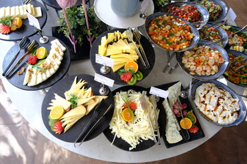 Open buffet area with various cheese, appetizers, meat and pastries for breakfast