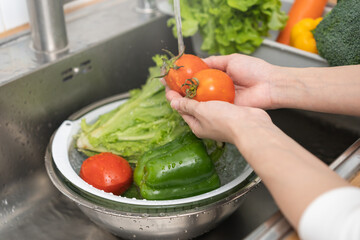 Close up tomato, asian young woman washing broccoli, carrot fresh vegetables, paprika with splash...