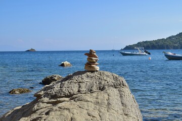 Balanced rock stack on a large, rough boulder on a beach on Skiathos island, Greece. Backdropped by...