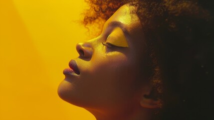 The profile portrait of an African American Fashion Model is dynamic and exciting. The model is a brunette with an afro hair style and has creative yellow make up on her lips and eyeshadows - obrazy, fototapety, plakaty