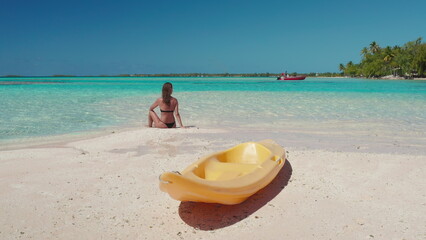 Tropical island Bora Bora paradise beach landscape. Woman relax sitting on white sand, yellow...