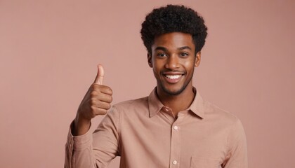 A friendly young man in a salmon pink shirt gives a thumbs up, with a warm smile against a pink background. - obrazy, fototapety, plakaty