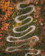 Aerial shot of a mountain winding road in autumn colors - obrazy, fototapety, plakaty