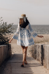 woman in hat walking to the beach