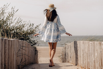 woman in hat walking to the beach