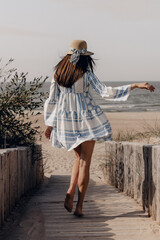 woman in hat walking to the beach