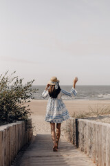 woman in hat walking to the beach
