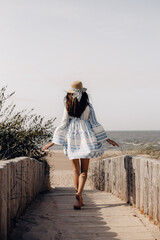 woman in hat walking to the beach