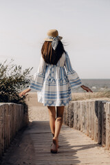 woman in hat walking to the beach