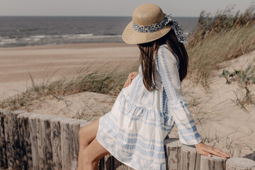 pregnant woman in hat sitting near the beach