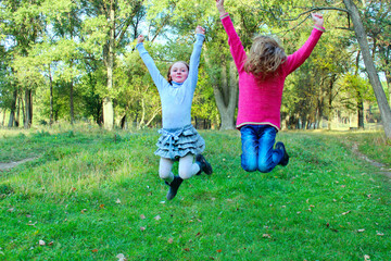 Young sisters jump in park. Happy childhood. Hovering in the air