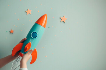 A toy rocket in the hands of a child on a light blue background, stars nearby, free space for text
