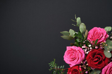 Holiday composition with bouquet of red and pink roses on black background. Space for your text.