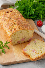 Zucchini bread with cheese, ham and fresh herbs on a wooden board on a gray background. Healthy food.