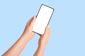 Female hands holding a phone with a blank screen on a blue background